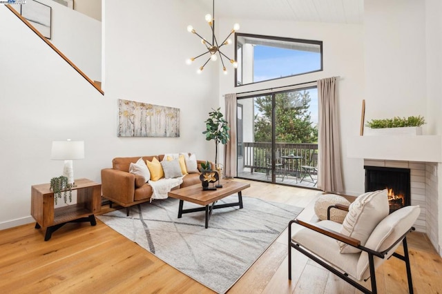 living room featuring an inviting chandelier, a fireplace, high vaulted ceiling, and light wood-type flooring