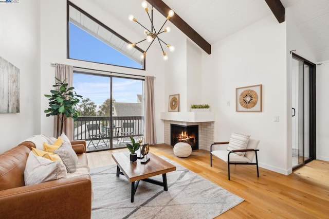 living room featuring an inviting chandelier, wood-type flooring, a brick fireplace, and beamed ceiling