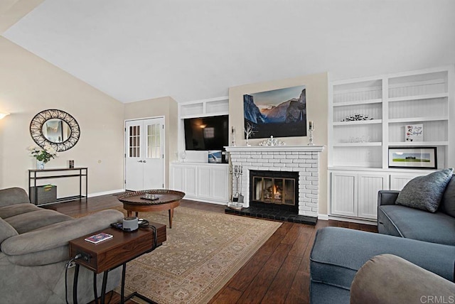 living room featuring vaulted ceiling, dark hardwood / wood-style floors, built in features, a fireplace, and french doors