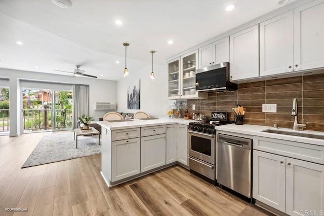 kitchen featuring sink, white cabinetry, decorative light fixtures, appliances with stainless steel finishes, and kitchen peninsula