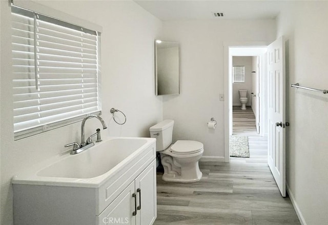 bathroom with hardwood / wood-style flooring, vanity, and toilet