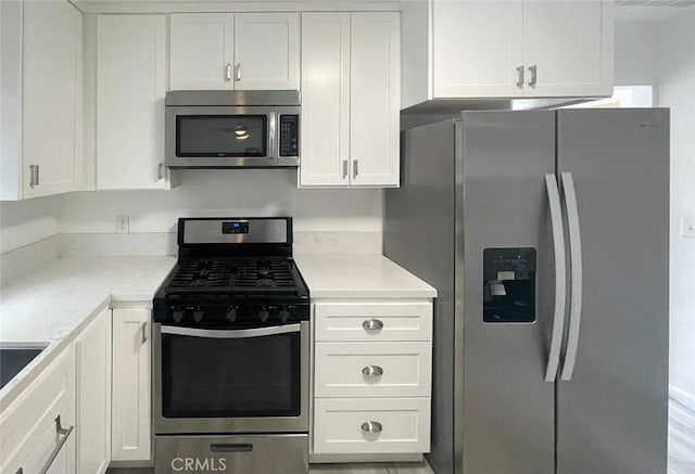 kitchen featuring white cabinetry, stainless steel appliances, and light stone countertops