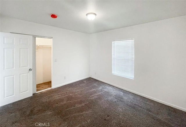 unfurnished bedroom featuring dark colored carpet and a closet