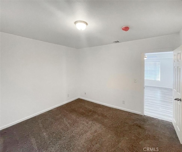 unfurnished room with dark carpet