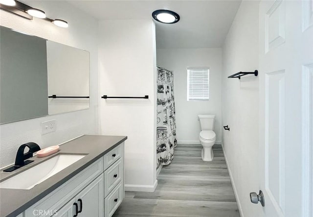 bathroom with hardwood / wood-style flooring, vanity, a shower with shower curtain, and toilet