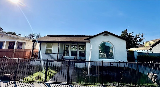 view of front facade with a fenced front yard, a porch, and stucco siding