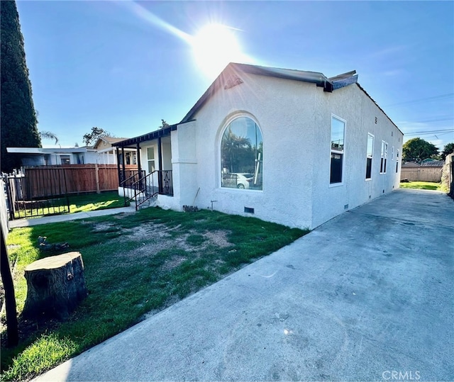 view of property exterior featuring crawl space, a lawn, fence, and stucco siding