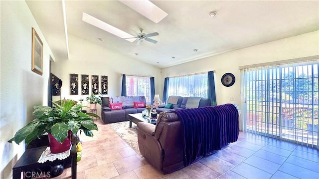 living room with a wealth of natural light, lofted ceiling with skylight, and ceiling fan