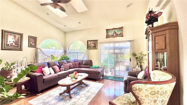 living room with ceiling fan, hardwood / wood-style flooring, a skylight, and a healthy amount of sunlight