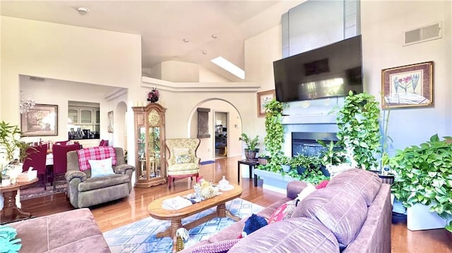 living room featuring hardwood / wood-style flooring, high vaulted ceiling, and a large fireplace