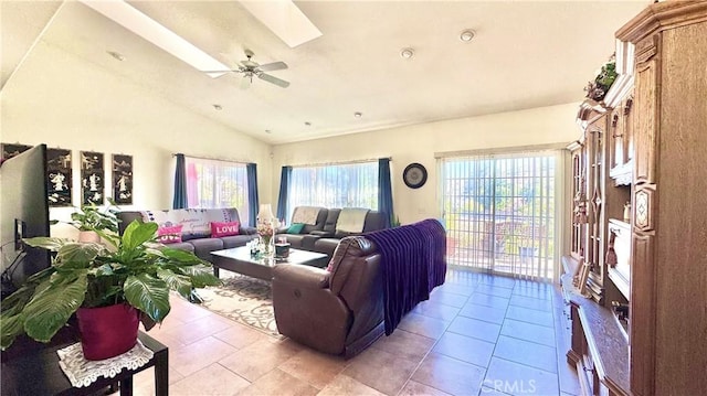 tiled living room with vaulted ceiling with skylight and ceiling fan