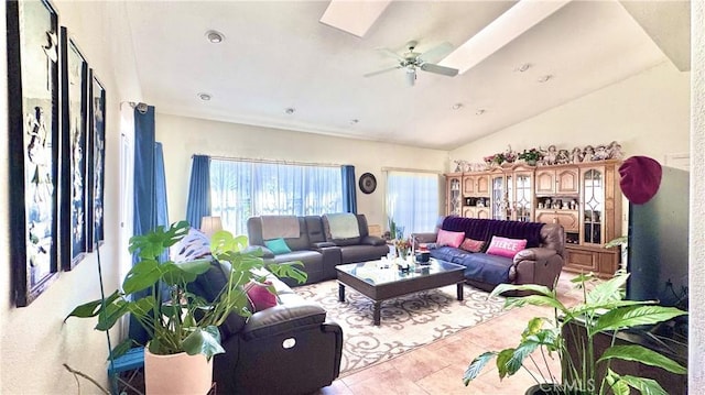 living room with lofted ceiling with skylight and ceiling fan