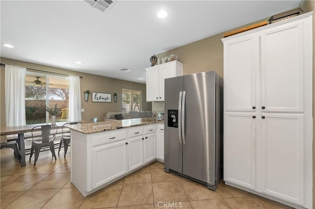 kitchen featuring stainless steel fridge with ice dispenser, white cabinets, light tile patterned floors, kitchen peninsula, and light stone countertops