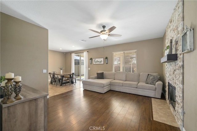 living room with a fireplace, dark hardwood / wood-style floors, and ceiling fan