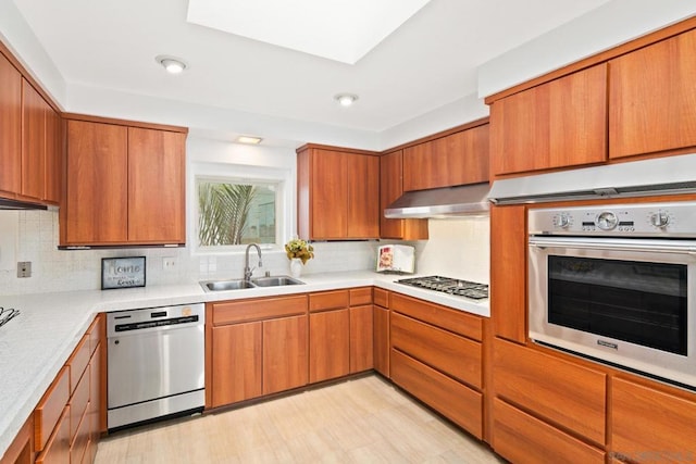 kitchen featuring tasteful backsplash, wall chimney range hood, sink, and appliances with stainless steel finishes