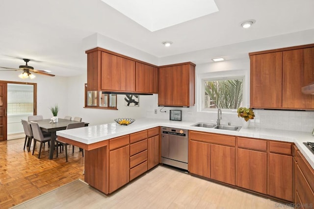 kitchen featuring tasteful backsplash, sink, stainless steel dishwasher, kitchen peninsula, and light parquet flooring