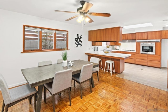 dining area with light parquet flooring, sink, and ceiling fan