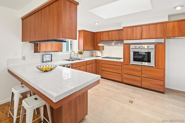 kitchen featuring range hood, tasteful backsplash, sink, oven, and kitchen peninsula