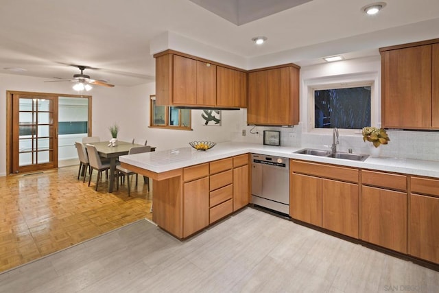 kitchen featuring sink, dishwasher, tasteful backsplash, kitchen peninsula, and light parquet flooring