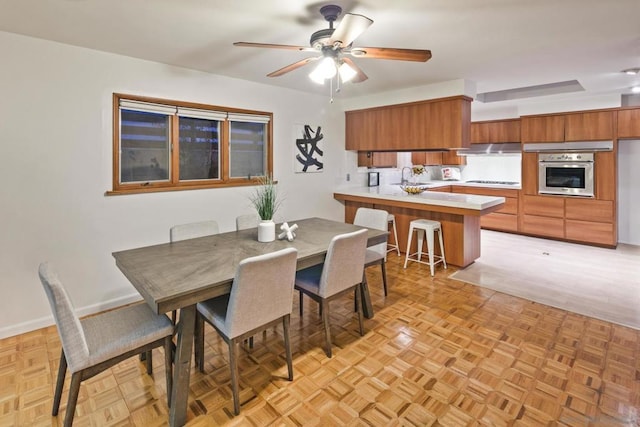 dining space with sink, light parquet flooring, and ceiling fan