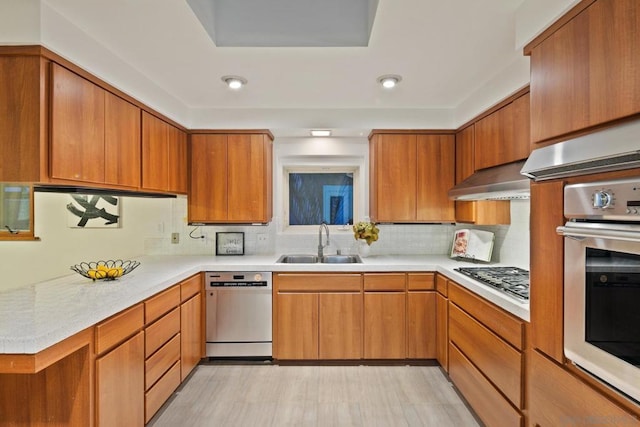 kitchen featuring backsplash, appliances with stainless steel finishes, sink, and wall chimney range hood