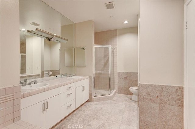 bathroom featuring toilet, an enclosed shower, tile walls, vanity, and tile patterned flooring