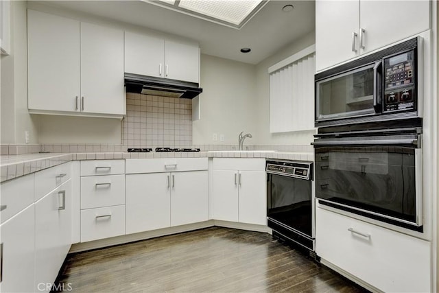 kitchen featuring sink, hardwood / wood-style flooring, backsplash, black appliances, and white cabinets