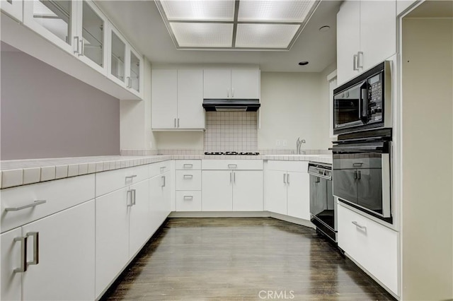 kitchen with dark hardwood / wood-style flooring, white cabinets, backsplash, and black appliances