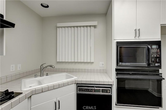 kitchen with tile counters, white cabinets, and black appliances