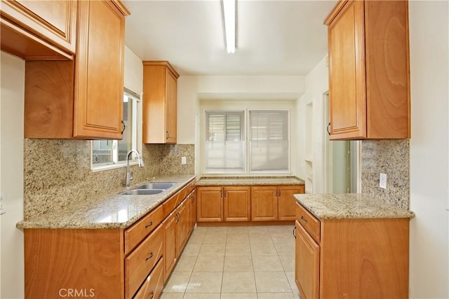 kitchen featuring backsplash, light stone countertops, sink, and light tile patterned floors