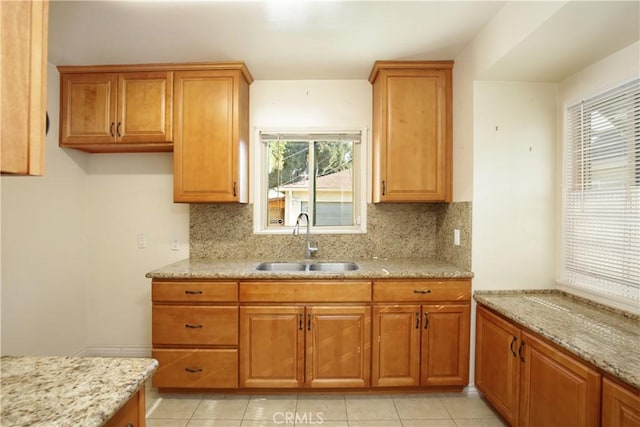 kitchen featuring light stone countertops, sink, and decorative backsplash