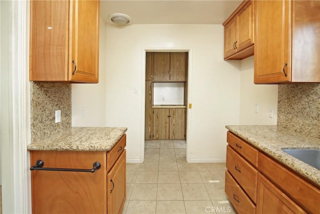 kitchen featuring light tile patterned floors, light stone counters, and decorative backsplash