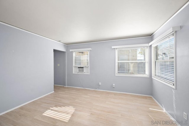 empty room featuring cooling unit, ornamental molding, and light hardwood / wood-style flooring