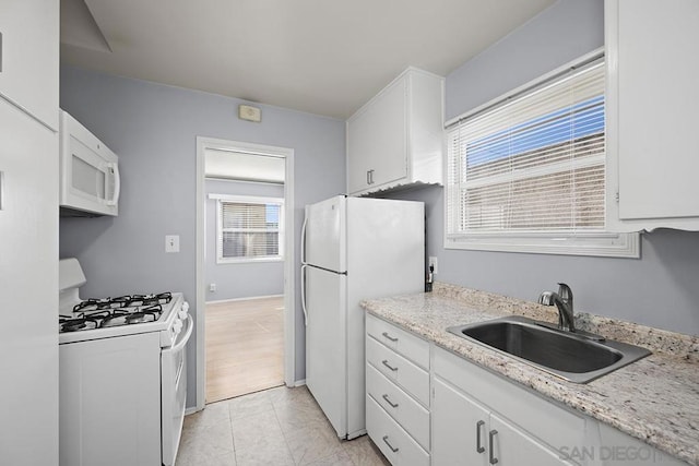 kitchen featuring light stone countertops, sink, white cabinets, and white appliances