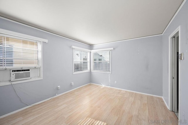 unfurnished room with cooling unit, crown molding, light wood-type flooring, and a wealth of natural light