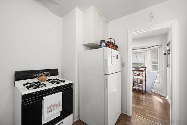 kitchen featuring gas range, white fridge, and white cabinets