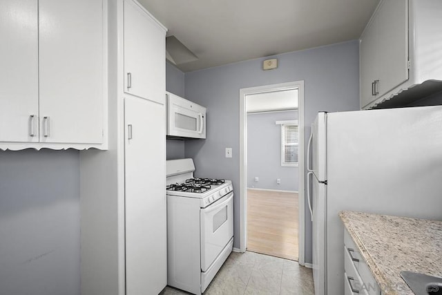 kitchen featuring white cabinetry, light stone countertops, and white appliances