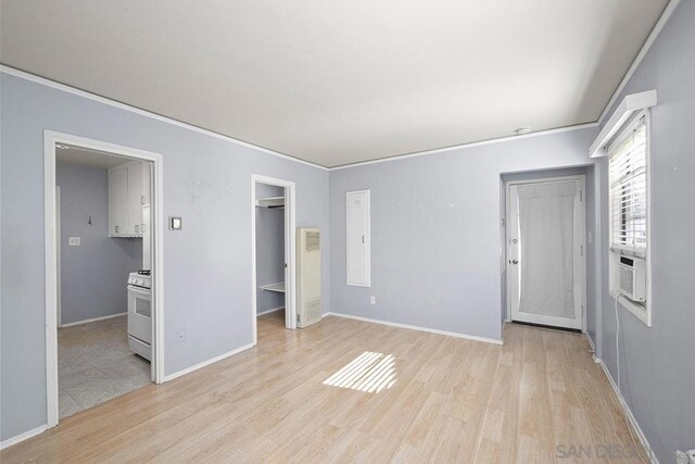 unfurnished bedroom featuring cooling unit, ornamental molding, a spacious closet, and light hardwood / wood-style floors