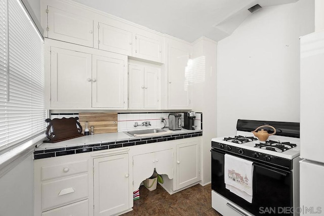 kitchen featuring tile countertops, sink, white cabinets, backsplash, and gas stove