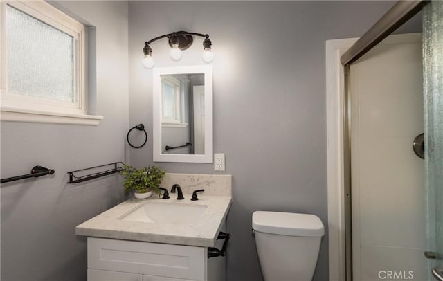 bathroom with walk in shower, vanity, and toilet