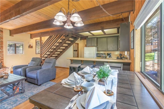 dining space with beamed ceiling, wood-type flooring, wood ceiling, and a chandelier