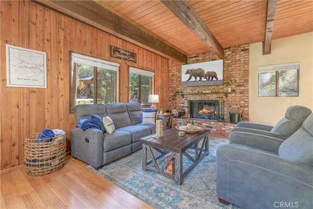 living room with wooden walls, hardwood / wood-style flooring, wood ceiling, a brick fireplace, and beam ceiling