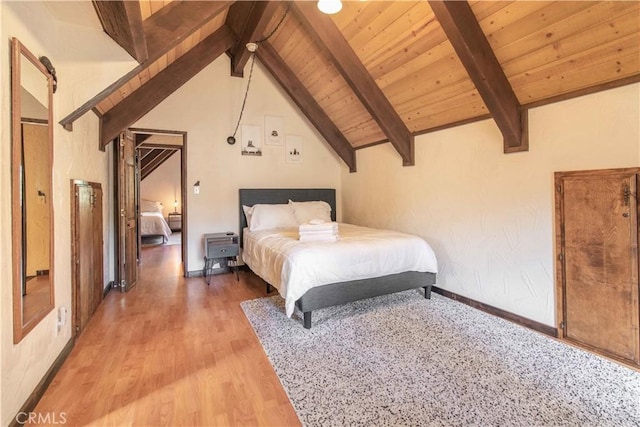 unfurnished bedroom with lofted ceiling with beams, a barn door, hardwood / wood-style floors, and wood ceiling