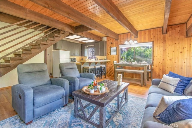 living room featuring beam ceiling, wood ceiling, wooden walls, and light hardwood / wood-style flooring