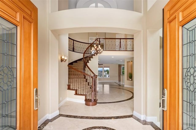 entrance foyer featuring a notable chandelier, baseboards, a high ceiling, and stairs