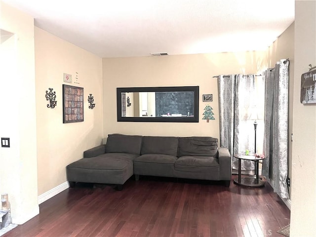 living room with wood finished floors, visible vents, and baseboards