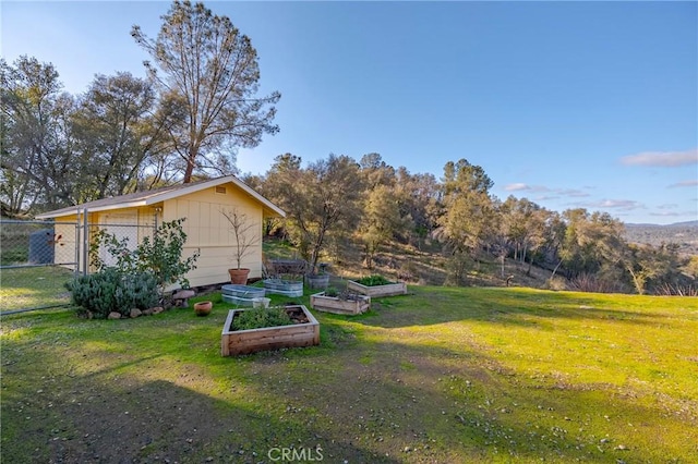 view of yard featuring a garden, fence, and an outdoor structure
