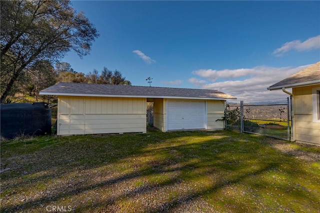 rear view of property featuring a garage, a gate, fence, and a yard