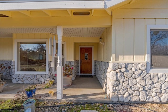 property entrance with covered porch and stone siding