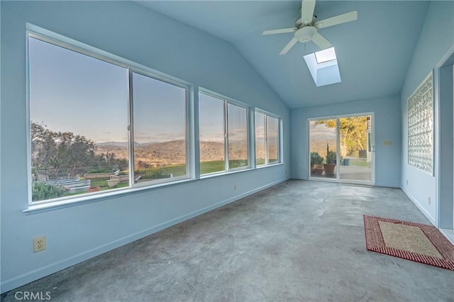 interior space featuring baseboards, a ceiling fan, and lofted ceiling with skylight